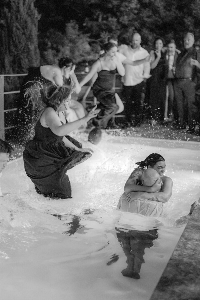 Reportage photo of bride and groom diving in a pool