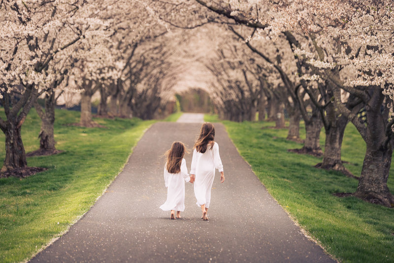 two girls walking on a drive with trees