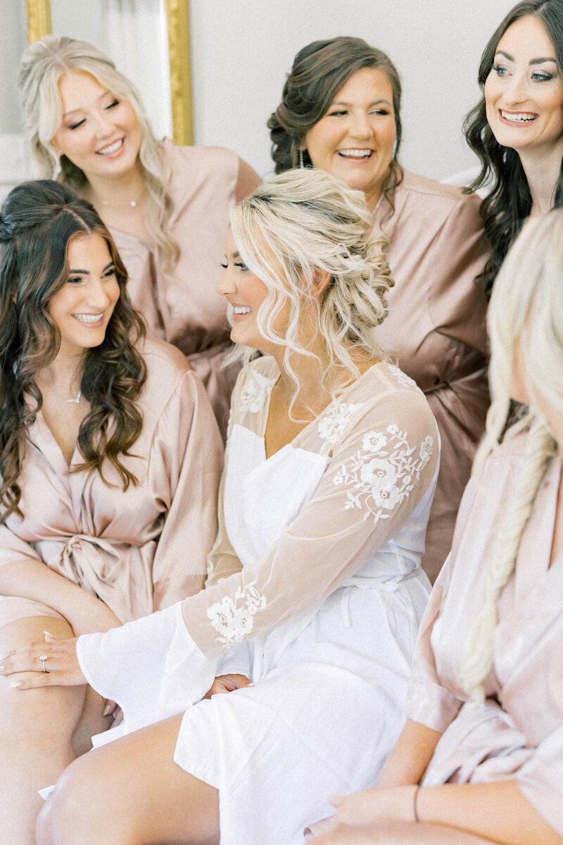 knoxville bride getting ready with her bridesmaids in rose colored robes smiling at one another at daras garden
