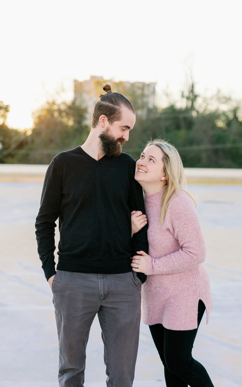 couple looking at each other smiling on rooftop parking garage