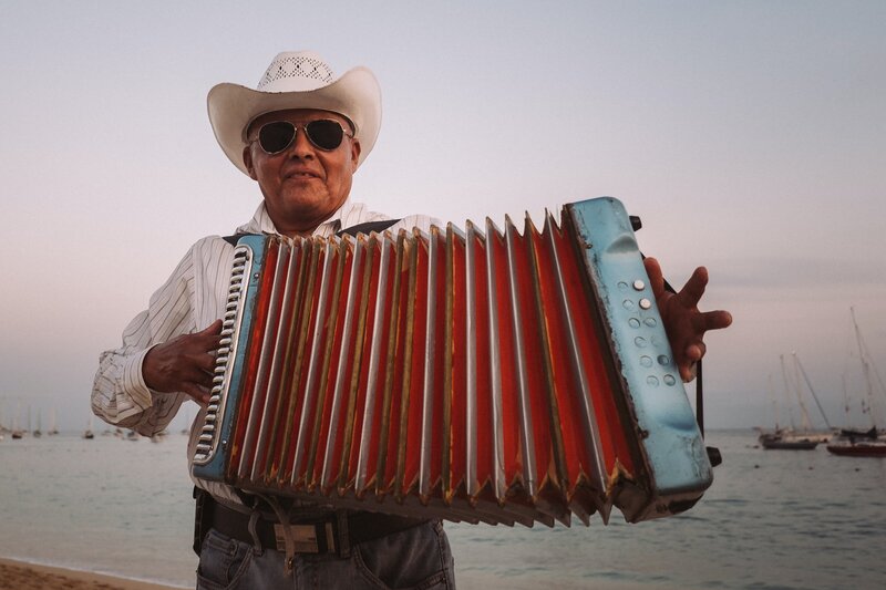 Man in glasses and white cowboy hat plays a red accordion