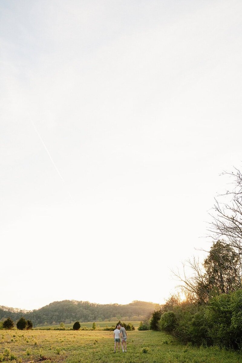 couple holding hands and walking in a field during golden hour in nashville
