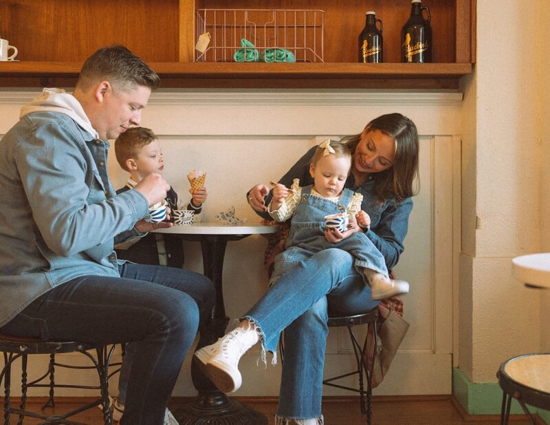 family of four eating in ice cream parlor with two small kids