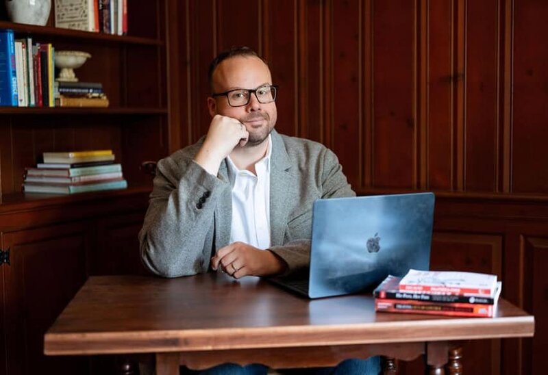 Dr. Mike, shown here sitting at his desk with his laptop open, has several speaking topics he can share with your audience.