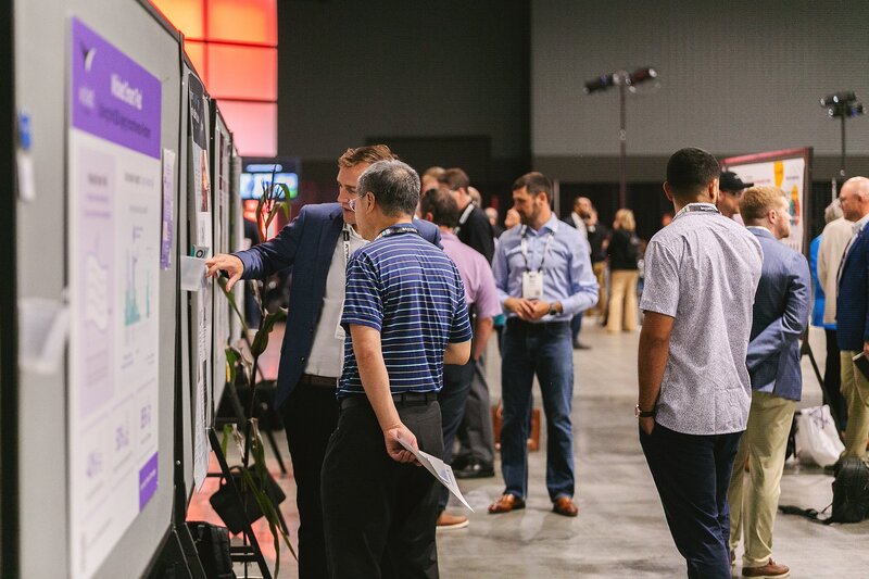 Two_professional_men_collaborating_at_a_vendor_bulletin_board_during_a_business_conference_at_the_Indiana_Convention_Center_in_Indianapolis_networking_and_sharing_ideas_for_event_services_vendors_and_corporate_partnerships