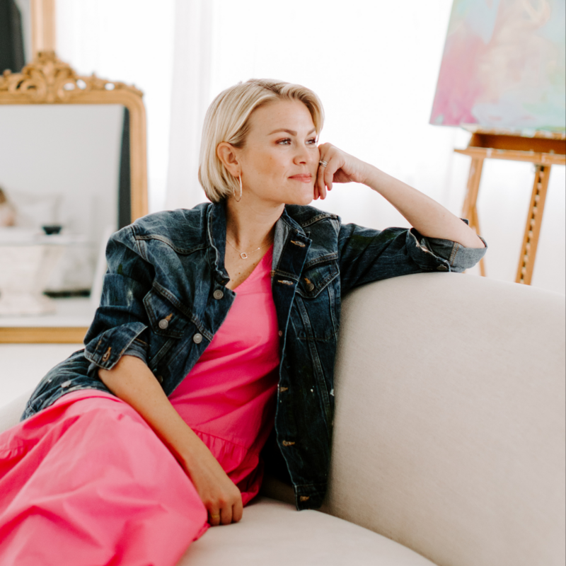 Abstract artist in pink dress on couch smiling