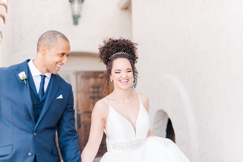 groom looking at bride as they hold hands and joyfully smile as they walk away from their ceremony by kari joy photography colorado wedding photography