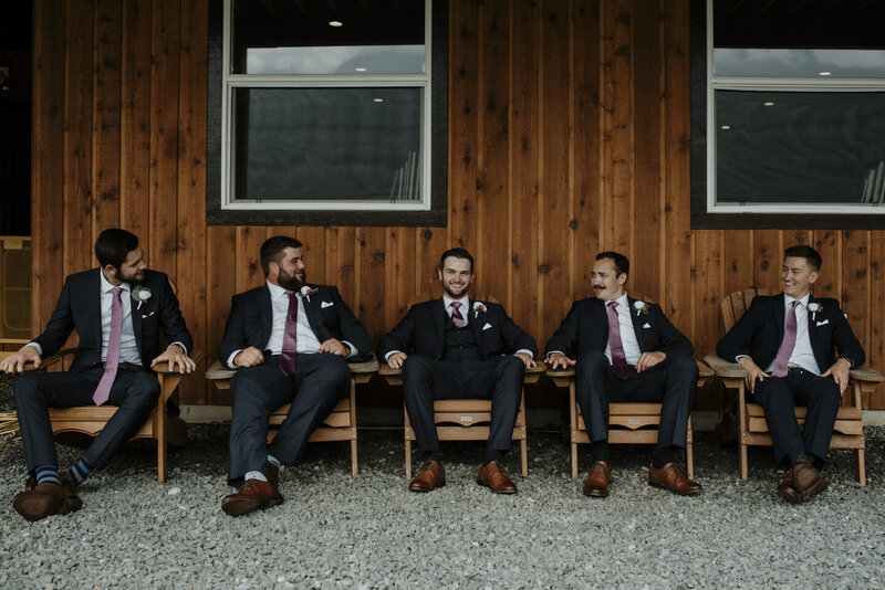 Groom and groomsmen sitting in lawn chairs outside of Fraser River Lodge Suits