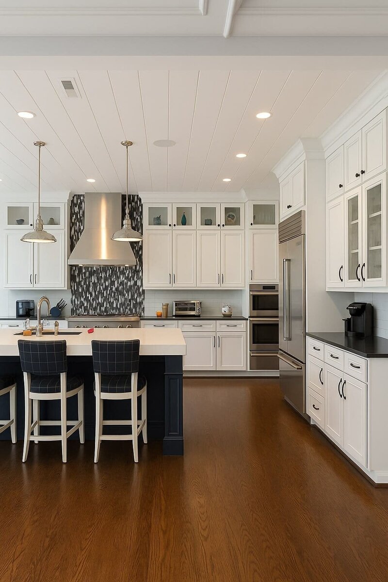 Spacious kitchen remodel with white cabinetry, navy island, pendant lighting, and stainless steel appliances.