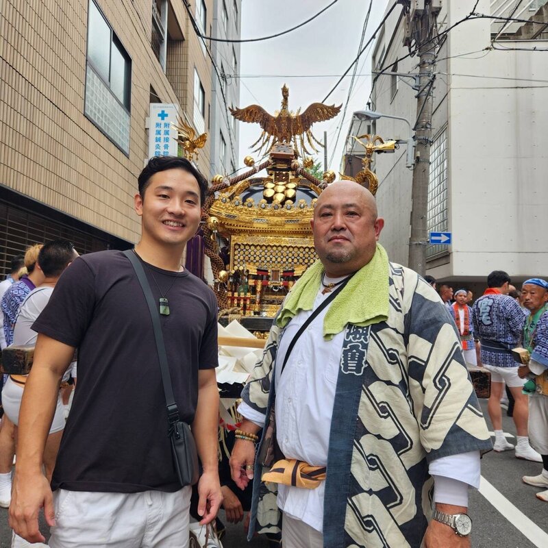 Japan Blend founder Yasushi smiling with a festival participant during a vibrant street celebration in Japan