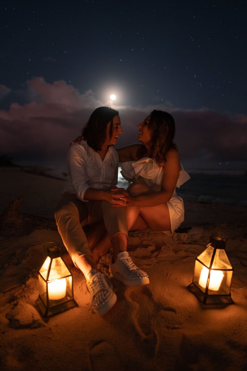 Couple sitting in the sand under the moonlight lit by lanterns on their Vanuatu wedding day