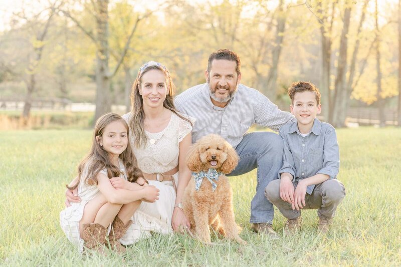 family of 4 squatting for photos with their dog during Prince William County, Virginia spring minis