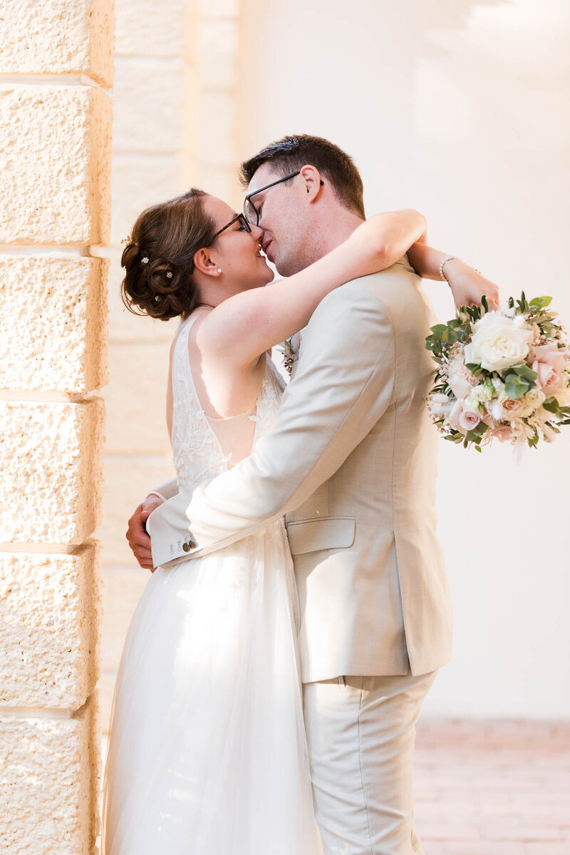 Brautpaar in inniger Pose küsst sich nach Ihrer Hochzeit in Schloss Schleißheim