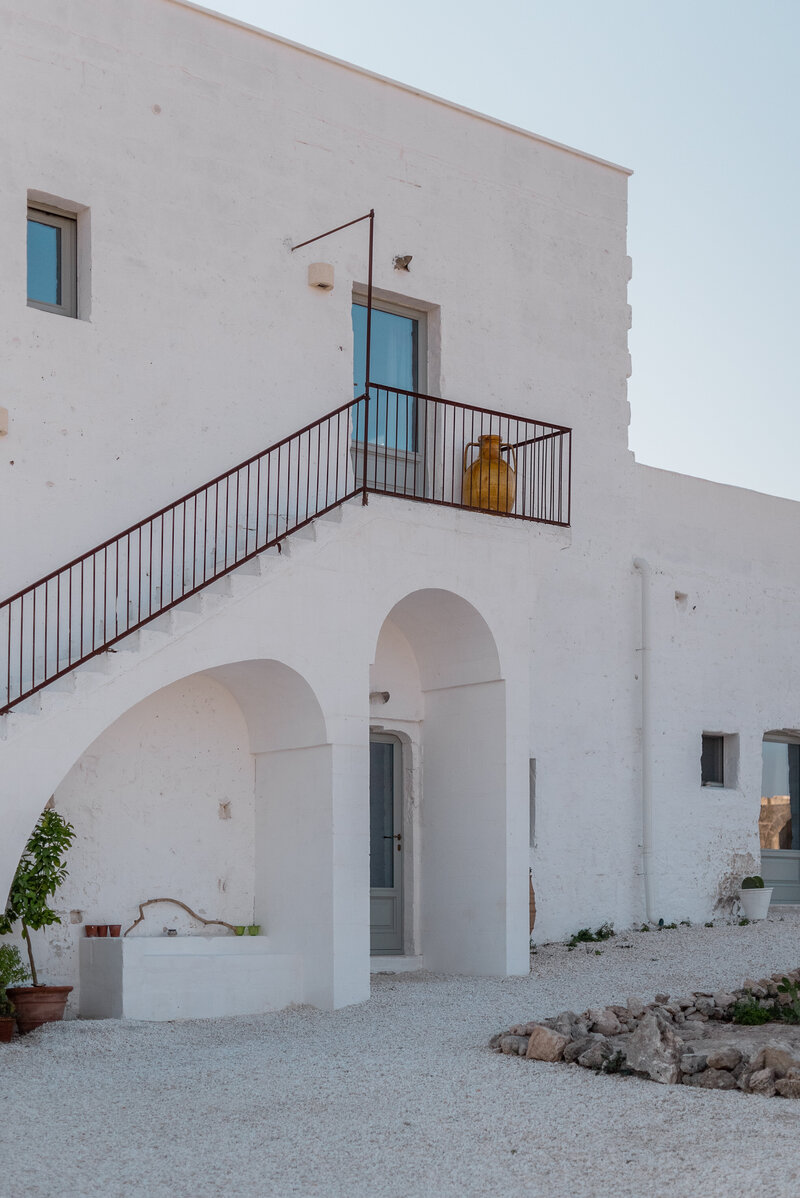 White Italian hotel with arched doorways and pots out front