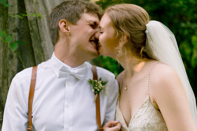 Bride and groom sharing a playful nose-to-nose moment outdoors.