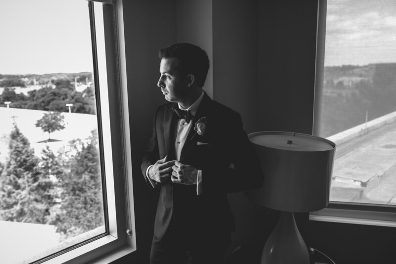 groom putting on jacket at wedding guest suite