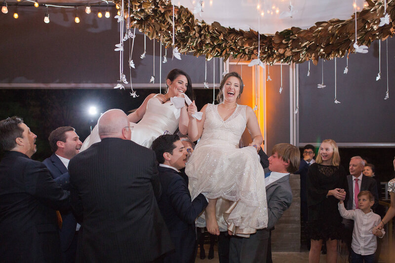two brides laugh as they are tossed in the air during their reception at The Dunlavy in Houston Texas by Swish and Click Photography