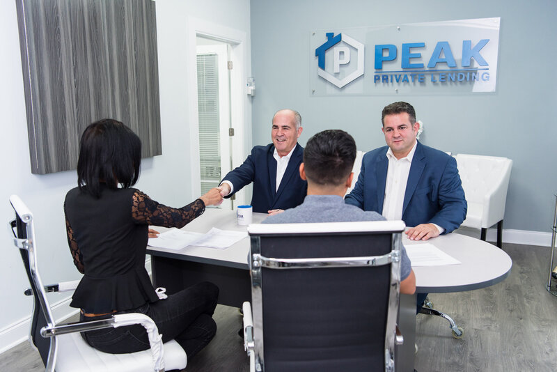 2 private lending representatives talking and shaking hand with their clients at the Peak Private Lending office in Teaneck.