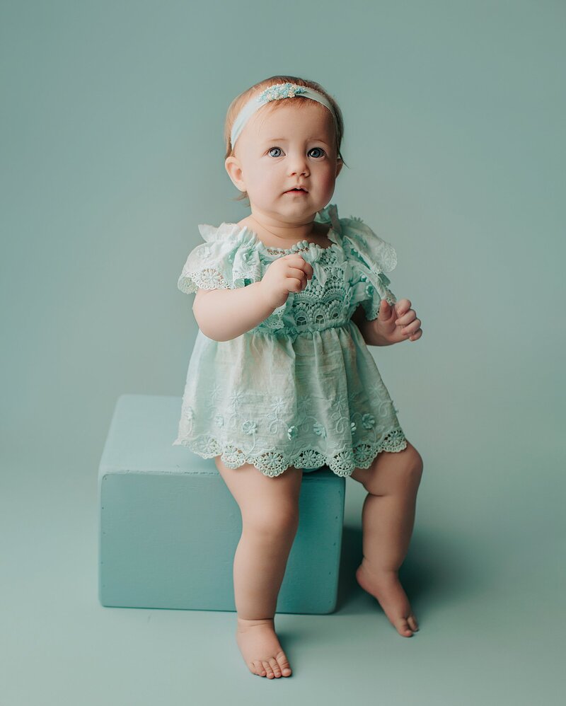 Baby waving at camera with big grin during milestone shoot