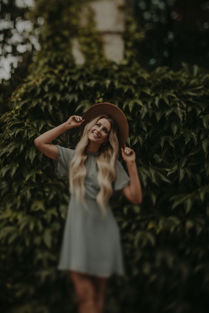 woman smiling holding hat on her head