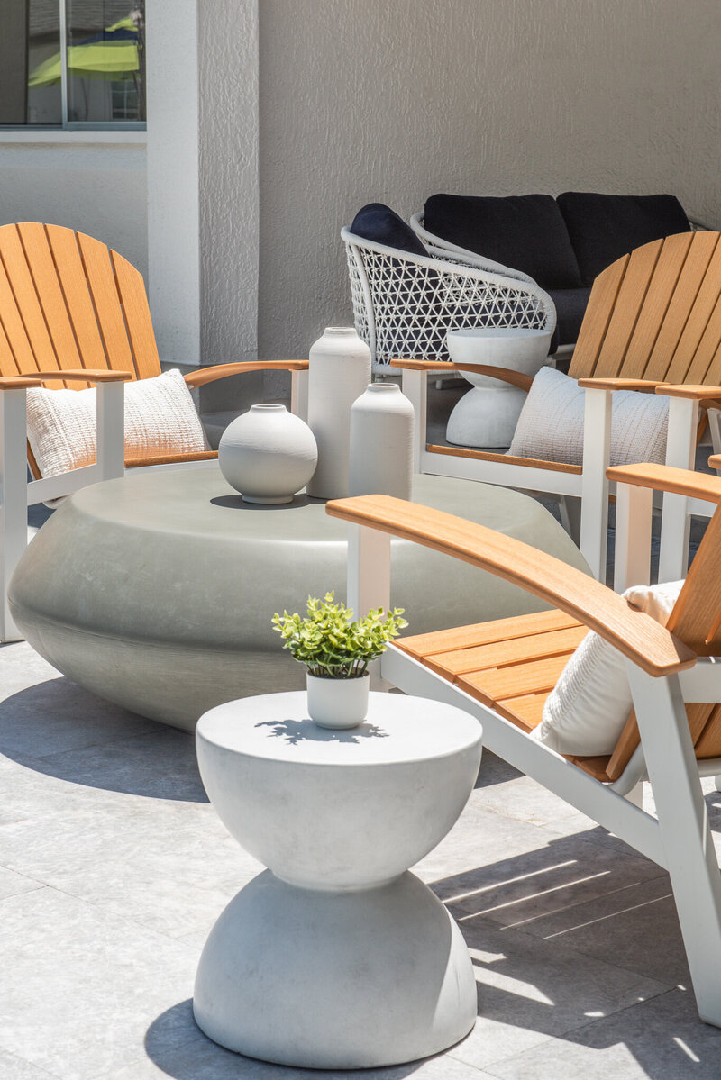 Commercial apartment pool design. Featuring a variety of bold seating, beautiful landscape design, string lights, and other amenities. Design by Gracious Home Interiors, luxury interior designer in Waxhaw, North Carolina and across the east coast.