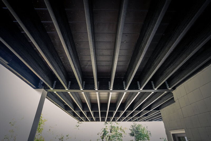 Underside of a composite deck with black composite lumber framing from Owens Corning. 