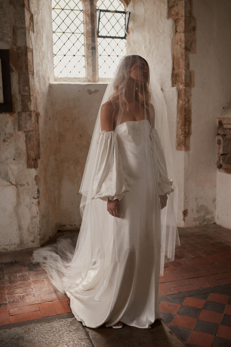 Corseted wedding dress with long sleeves, worn by blonde bride
