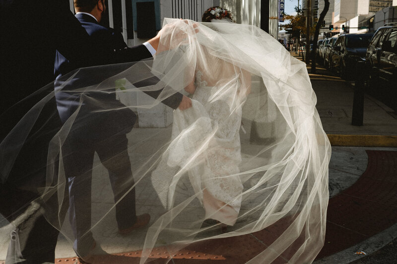 a bride rushes past her wedding dress hanging in the doorway in this documentary style wedding image