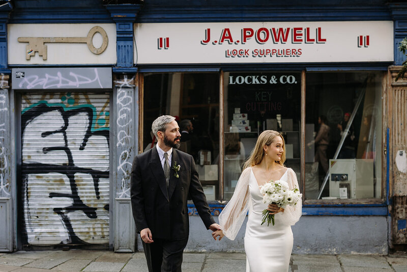 Bride and groom walking across the street in front of J.A. Powell in Dublin, Ireland