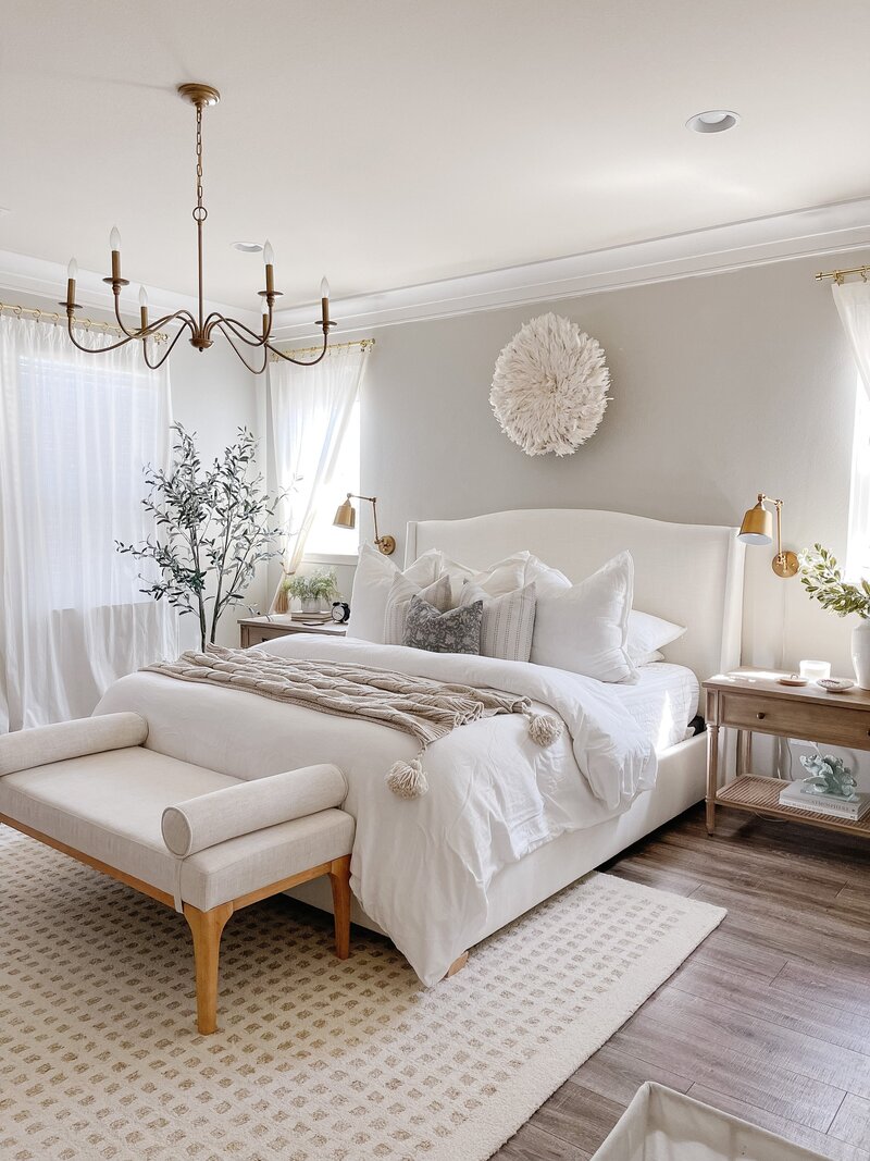 a bedroom with elevated neutral furniture and decor