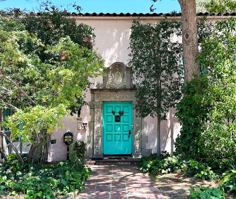 Historic homes designer photo tours in Los Angeles old home architecture features a pink Mediterranean Revival home with a turquoise door and classic details.