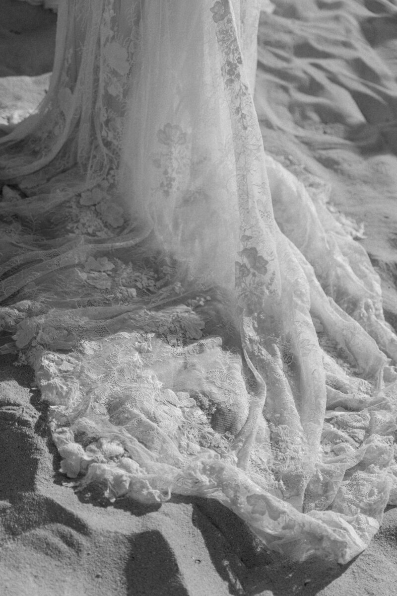 Bride's wedding dress in black and white photography on a beach.