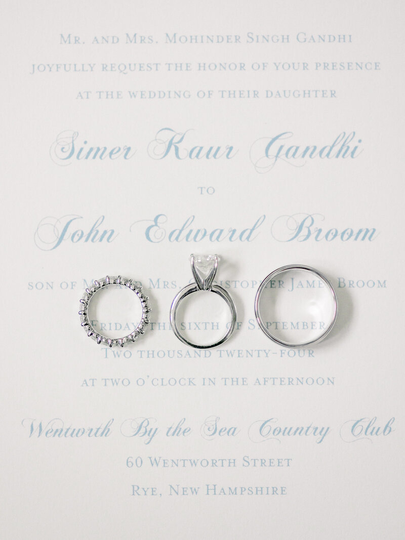 Close up of wedding and engagement ringss on a wedding invitation