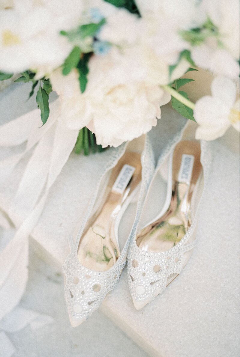 bride-shiny-white-pointed-shoes-stand-marble-step-near-wedding-bouquet