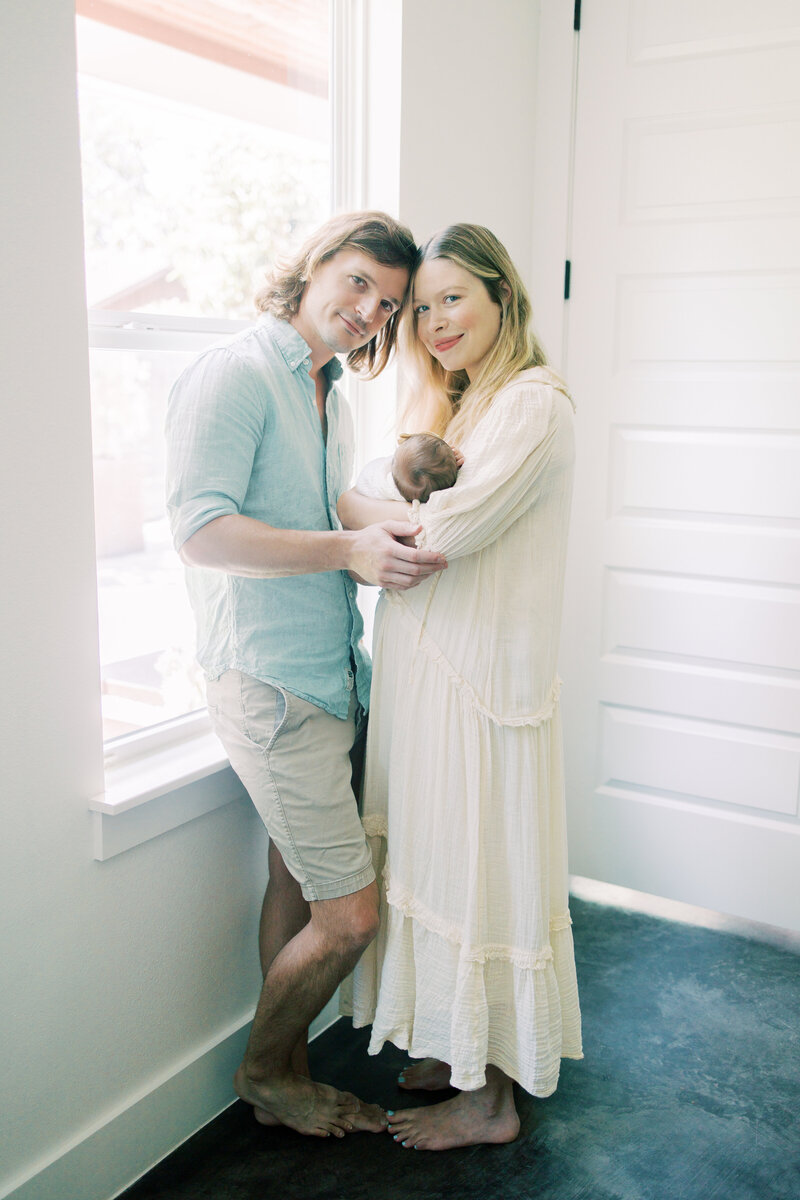 Austin newborn parents smile holding while holding their baby.
