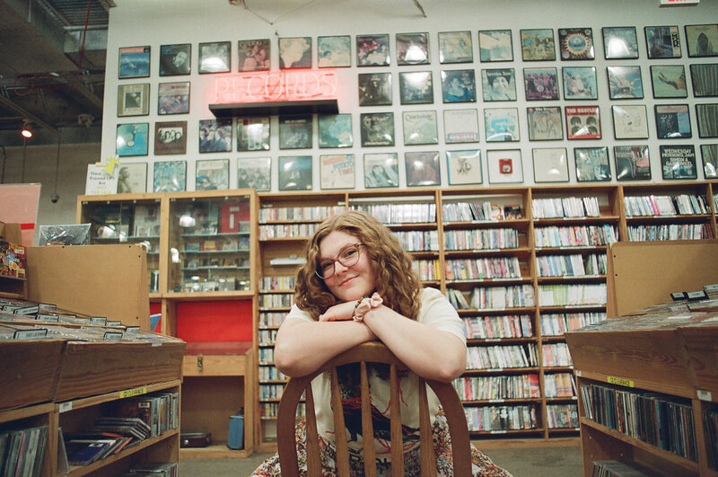 Allison Bolin Texas wedding photographer sitting on a chair in front of bookshelves