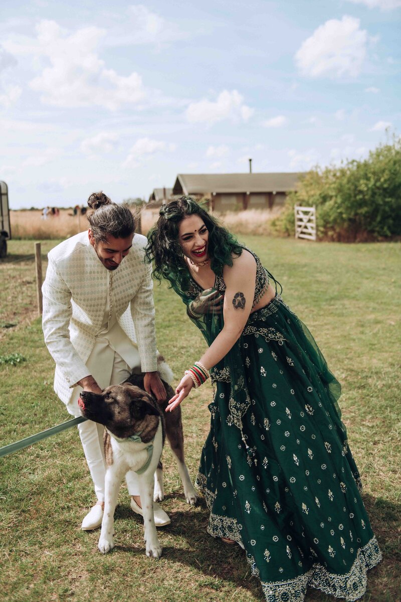 Asian bride and groom cuddling their beloved dog on their wedding day