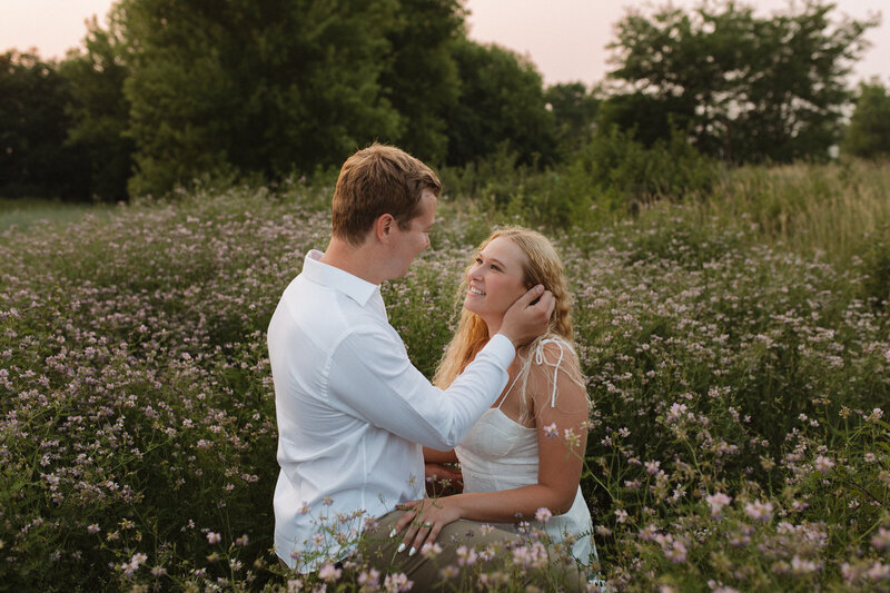 man and woman embracing while standing in a field of flowers
