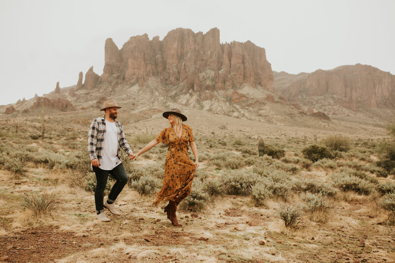 man and woman walking through desert