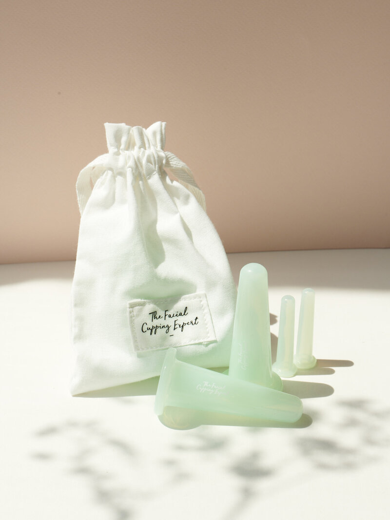 Close-up photo of facial cupping tools next to a small cloth bag.
