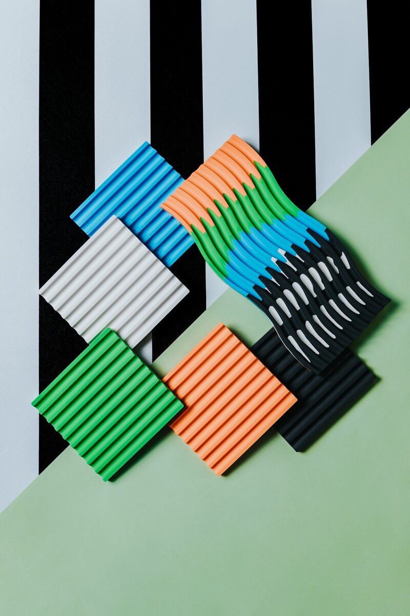 Black and white striped backdrop with multiple variously colored paint molds.