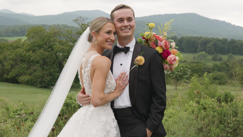 Husband and wife smile together with floral bouquet at Pippin Hill Vineyard and Farm in Charlottesville, Virginia
