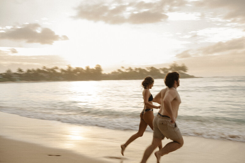 a couple runs on the beach in North Shore after their Hawaii elopement