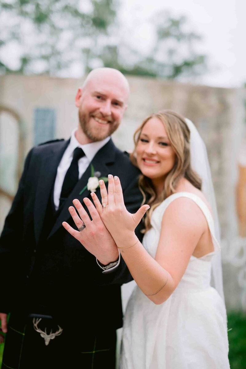 bride and groom showing off rings