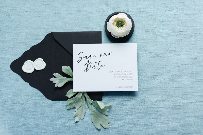 Black and white save the date card and envelope on a blue styling mat.