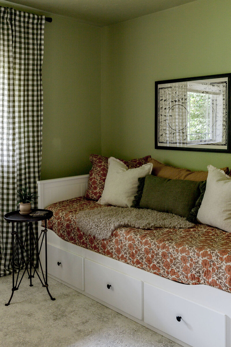 A day bed with floral linens next to a window with gingham curtains, representing a farmhouse interior design by Winsome Home Interiors.