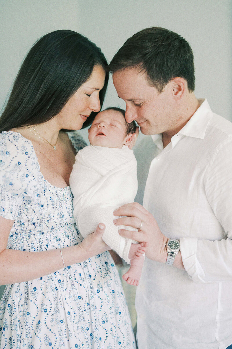 mom and dad kissing newborn baby's head
