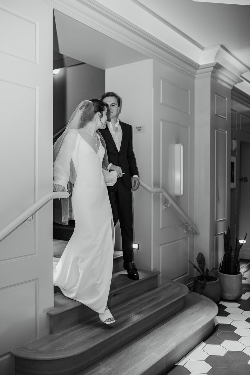 Bride and groom walking down hotel staircase