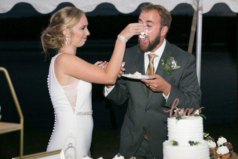 Bride putting cake on groom's face | Klein Wedding at Grace on the Lake in Maine taken by Maine Wedding Photographer