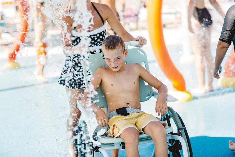 Young disabled boy in wheel chair enjoying water at Hersheypark splash pad